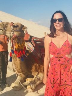 Sandra Hodes standing beside a camel in the desert